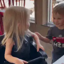 Toddler boy hugs blonde girl in high chair