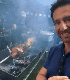 Man smiling with pig roast in background