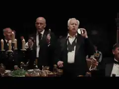 Men in tuxedos react with shock at dinner