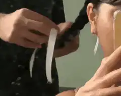 Hands tying a white ribbon in a braid