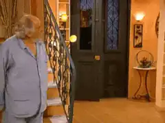 Man with paper bag head enters house