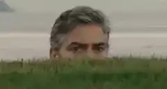 George Clooney peeking over grass