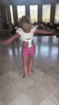Woman in pink shorts dancing in living room