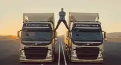 Man straddles two trucks