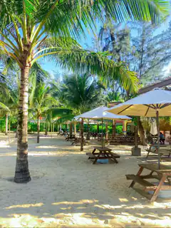 beachside picnic tables under umbrellas