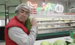 man hugging watermelon in grocery store