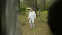 Man in white suit dancing in woods