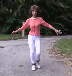 Woman in pink jacket dancing on path