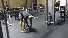 Man doing ab wheel rollouts in gym