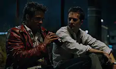 Two men sitting outside at night drinking