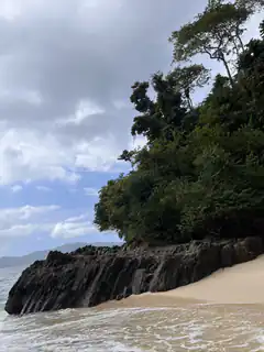 rocky cliff and beach under cloudy sky