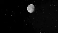 Moon drifting across starry night sky