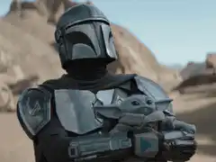 The Mandalorian holding Grogu