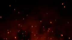 Orange sparks rising in dark smoke