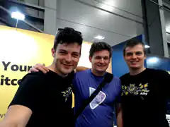 Three men posing for a selfie at a convention