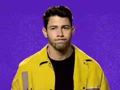 Nick Jonas waving with a smirk