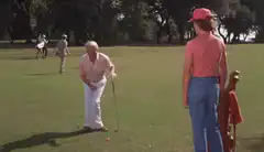 Old man golfing with a caddy