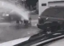man crawling under fire hydrant spray