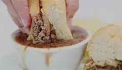 Dipping a French dip sandwich in au jus
