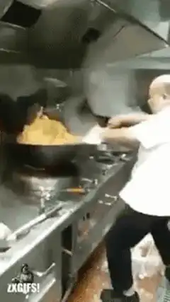 Chef flambéing food in a wok