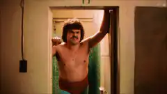 Shirtless man in doorway flexing