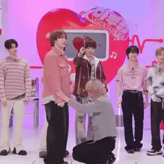 K-pop group member kneels to hold hand