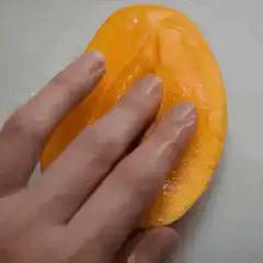 Hand pressing into mango