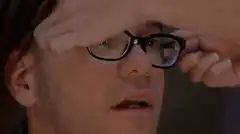 Man lifts glasses to reveal wide eyes