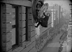 Man hanging from a clock on a building