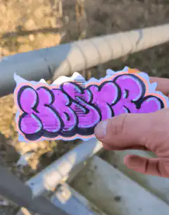 Hand applying purple graffiti sticker