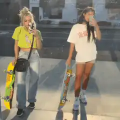 Two girls taking mirror selfies with skateboards