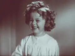 Shirley Temple laughing and covering mouth