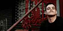 Rami Malek smirking with phone
