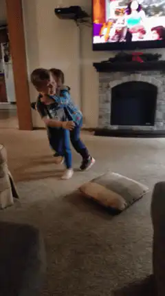 Boy pulls another boy across the carpet