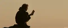 Silhouette of person reading on rock