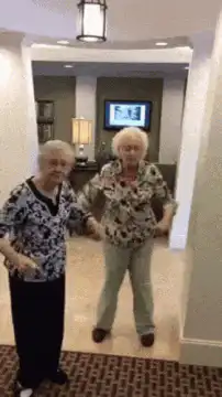 two elderly women dancing in a hallway
