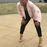 Woman in pink blazer laughing on pavement