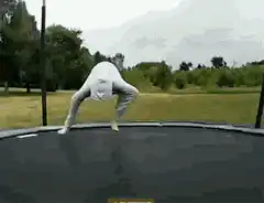 Person in white suit does backflip on trampoline