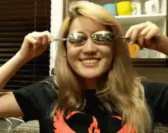Woman holding spoons over eyes