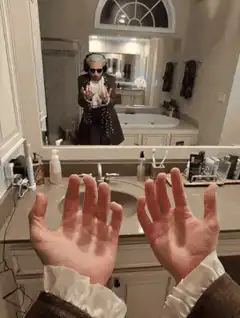 person washing hands in bathroom mirror