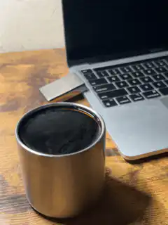 steaming coffee cup next to laptop