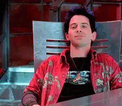 Charlie Sheen smirking in red shirt