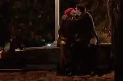 Couple kissing on a bench at night