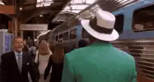 Man in green suit and white hat at train station