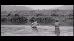 Two men wading through a river