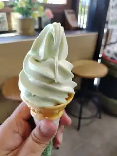 hand holding matcha soft serve ice cream cone