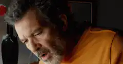 Man sneezes into his hand