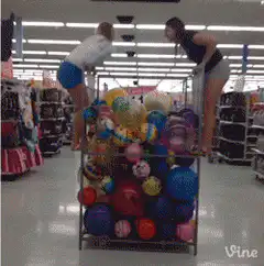 Two girls jump into a ball pit in a store