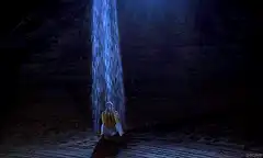 Man sitting under waterfall in dark cave