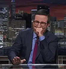 John Oliver laughing and waving